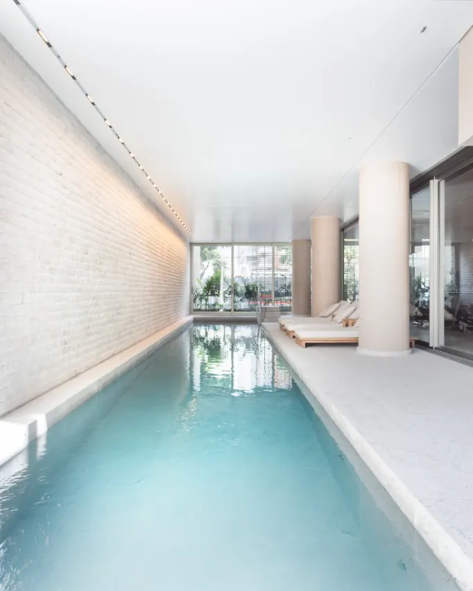 Piscina coberta de raia do condomínio Casa Leopoldo, junto a uma parede de tijolos